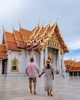 Wat Benchamabophit temple in Bangkok Thailand, The Marble temple in Bangkok. Asian woman with hat and European men visiting a temple, a couple on a city trip in Bangkok