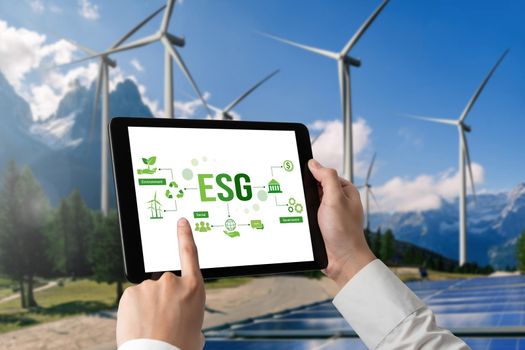 Green business transformation for environment saving and ESG business concept. Businessman using tablet to set corporate goal toward environmental friendly management and alternative clean energy use.