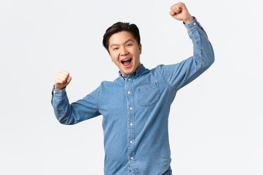 Successful winning man rejoicing over victory, raising hands up in hooray gesture, saying yes, achieving goal, winning prize, become champion and triumphing over great news, white background.