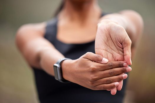 A healthy lifestyle is physically demanding. an unrecognizable woman holding her hand out and moving her wrist while jogging outdoors