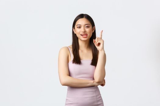 Luxury women, party and holidays concept. Creative attractive asian woman in evening dress have suggestion, raise index finger in eureka sign, propose solution or idea, white background.