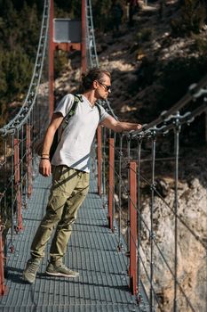 Hiker standing on hanging bridge and looking down to the lake. Travel concept.