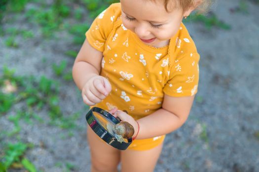 The child looks at the snail. Selective focus. Animal.