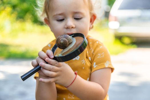 The child looks at the snail. Selective focus. Animal.