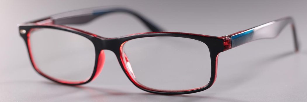 Fashionable plastic glasses red-black on gray background. Choice of stylish optics concept