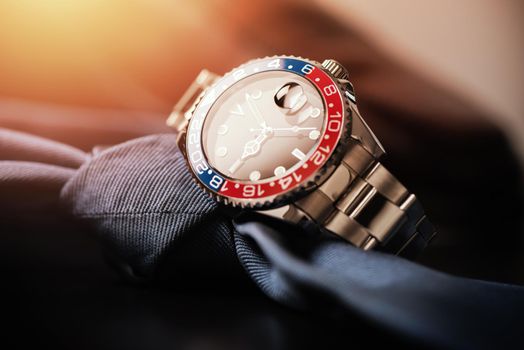 closeup luxury wristwatch for men with black dial blue-red bezel and stainless steel bracelet.