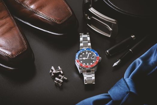 men's accessories, closeup at wristwatch with black dial blue-red bezel and stainless steel bracelet.