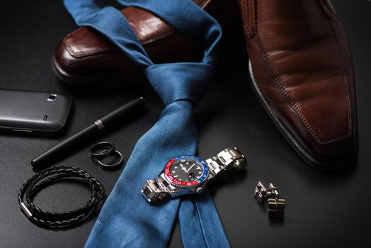 men's accessories, closeup at wristwatch with black dial blue-red bezel and stainless steel bracelet.