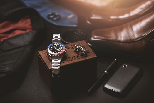 men's accessories, closeup at wristwatch with black dial blue-red bezel and stainless steel bracelet.