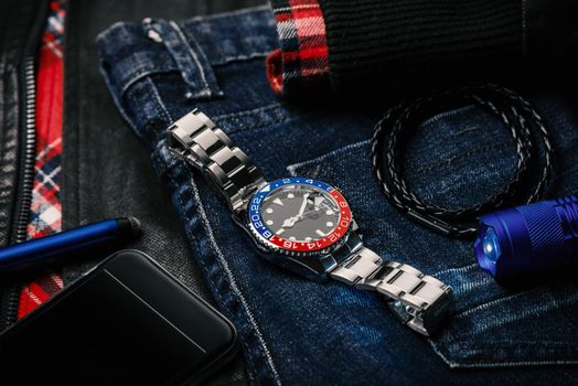 men's accessories, closeup at wristwatch with black dial blue-red bezel and stainless steel bracelet.