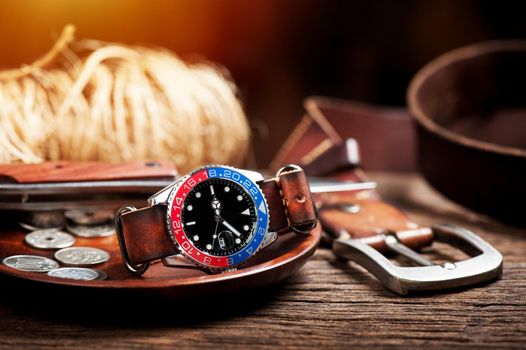 closeup luxury wristwatch for men with black dial blue-red bezel and leather strap.