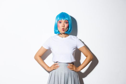 Portrait of beautiful korean girl pouting coquettish, looking at camera silly, standing in blue wig and party costume for halloween.