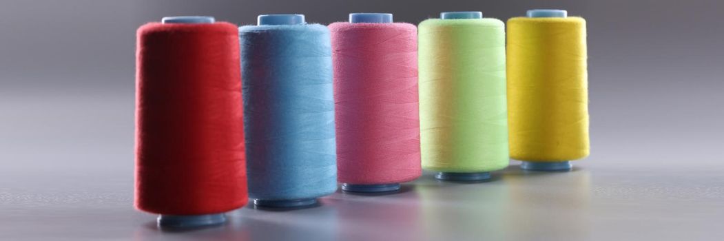 Fabric threads of different colors on gray background. Items for sewing textiles concept