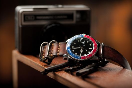 closeup luxury wristwatch for men with black dial blue-red bezel and leather strap.