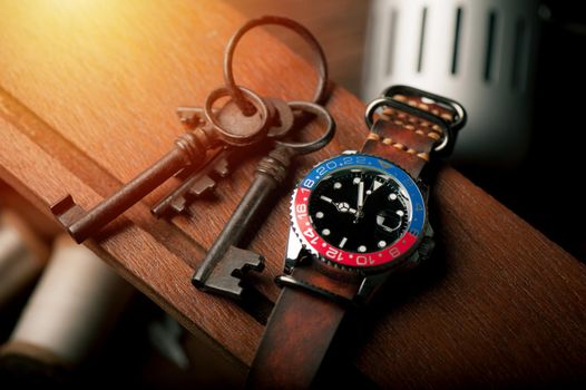 closeup luxury wristwatch for men with black dial blue-red bezel and leather strap.