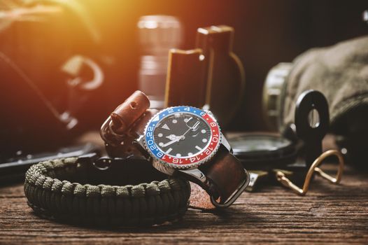 closeup luxury wristwatch for men with black dial blue-red bezel and leather strap. wristwatch with vintage men's objects.