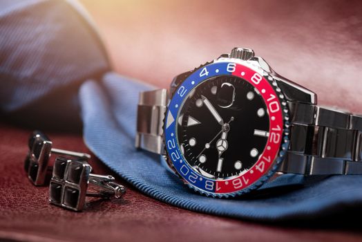 closeup luxury wristwatch for men with black dial blue-red bezel and stainless steel bracelet.