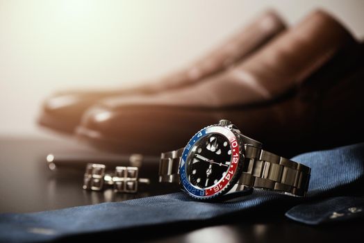 men's accessories, closeup at wristwatch with black dial blue-red bezel and stainless steel bracelet.