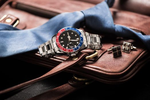 men's accessories, closeup at wristwatch with black dial blue-red bezel and stainless steel bracelet.