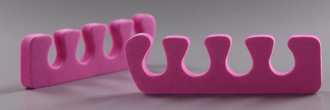 Pink toe divider on gray background. Pedicure accessory concept