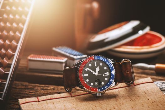 closeup luxury wristwatch for men with black dial blue-red bezel and leather strap.