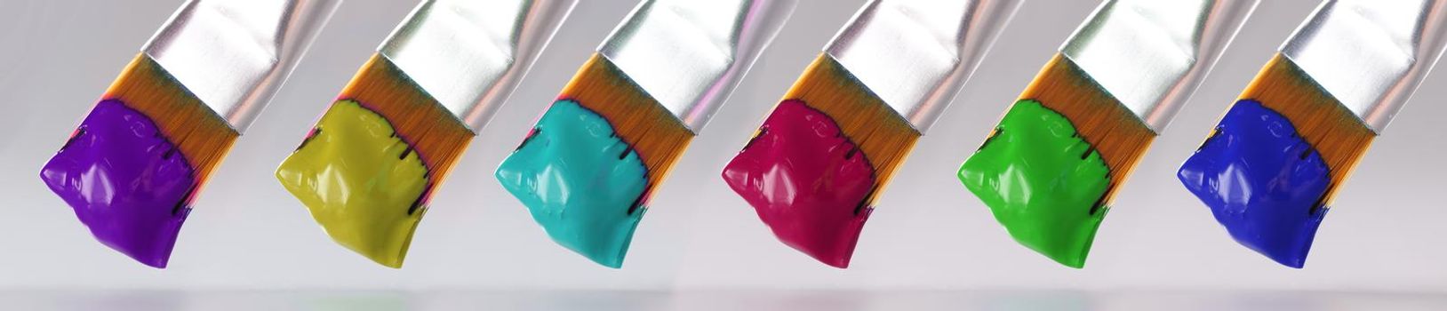 Three brushes with different paint colors. Artistic paints of different colors concept