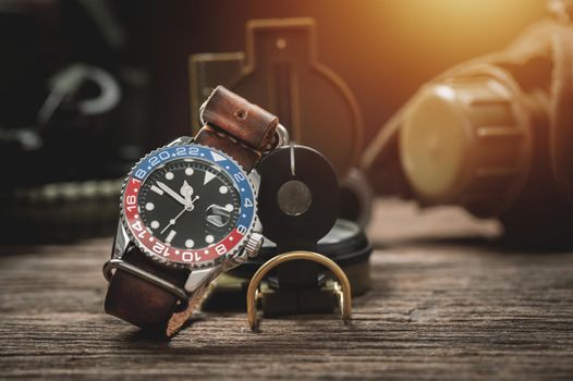 closeup luxury wristwatch for men with black dial blue-red bezel and leather strap. wristwatch with vintage men's objects.