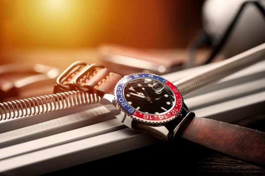 closeup luxury wristwatch for men with black dial blue-red bezel and leather strap.