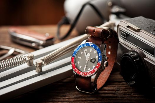 closeup luxury wristwatch for men with black dial blue-red bezel and leather strap.