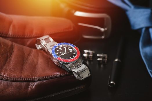 men's accessories, closeup at wristwatch with black dial blue-red bezel and stainless steel bracelet.