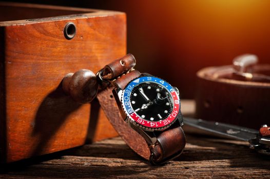 closeup luxury wristwatch for men with black dial blue-red bezel and leather strap.