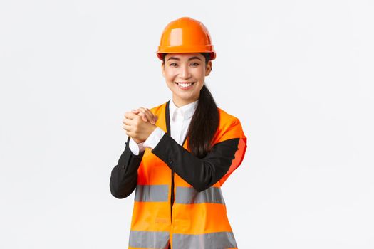 Successful winning female asian architect shaking hands together, achieve goal. Chief construction manager celebrating victory, finish of building works, standing white background delighted.