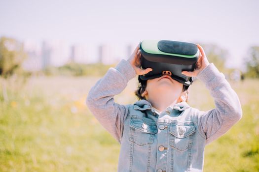 A boy is playing virtual reality glasses on the street . Modern gadgets. Children's games. The choice of virtual glasses. An article about virtual glasses. Modern children. Copy Space