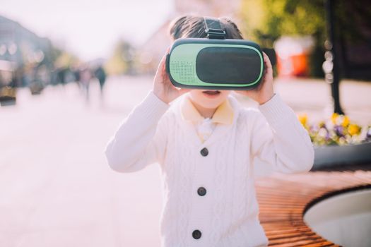 A boy is playing virtual reality glasses on the street . Modern gadgets. Children's games. The choice of virtual glasses. An article about virtual glasses. Modern children. Copy Space