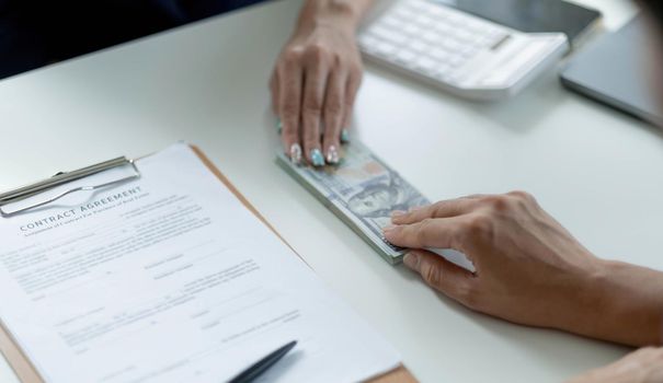 Businessman giving of money, cash dollars to his partner over an office desk - loan, payment and bribery concepts.