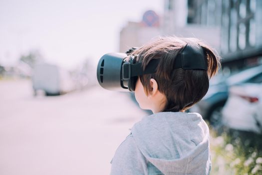 A boy is playing virtual reality glasses on the street . Modern gadgets. Children's games. The choice of virtual glasses. An article about virtual glasses. Modern children. Copy Space