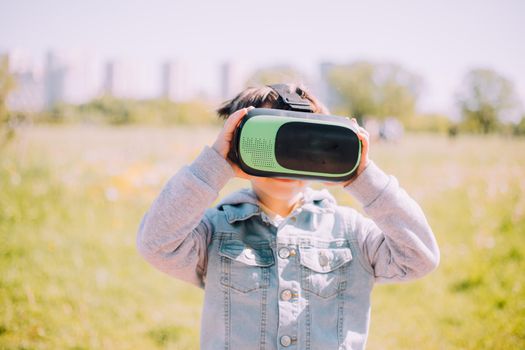 A boy is playing virtual reality glasses on the street . Modern gadgets. Children's games. The choice of virtual glasses. An article about virtual glasses. Modern children. Copy Space