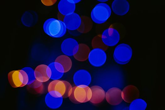 Blurred background. Bokeh garlands with yellow and blue lights. It can be used for decoration of Christmas or New Year themes. Unfocused abstract background. Selective focus.