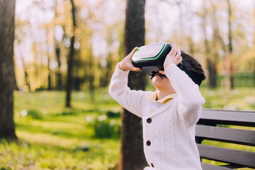 A boy is playing virtual reality glasses on the street . Modern gadgets. Children's games. The choice of virtual glasses. An article about virtual glasses. Modern children. Copy Space