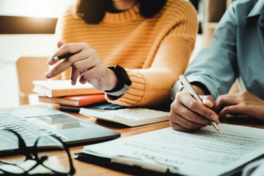 focus consultant holding a pen and the business owner holding a pen reading the terms of a joint venture contract with a partner company