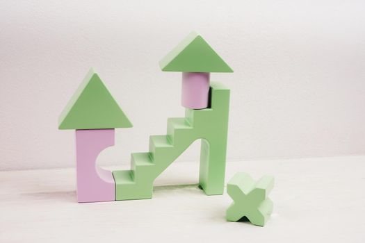 Children's wooden construction kit. Toys made of natural material. Figures from a lilac and green wooden construction. Popular colors 2022 - very peri. Toy for developing a child's creative thinking.