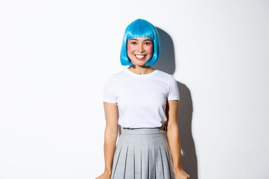 Excited asian girl in blue short wig looking upbeat, smiling at camera joyfully.