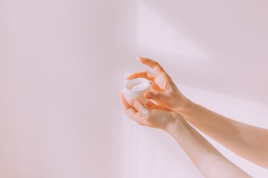 Women's hands hold a cosmetic copy space cream . An article about care cosmetics. Hand cream. Face cream.