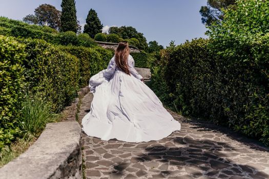 a beautiful woman with long brown hair runs along a path along beautiful bushes in the park