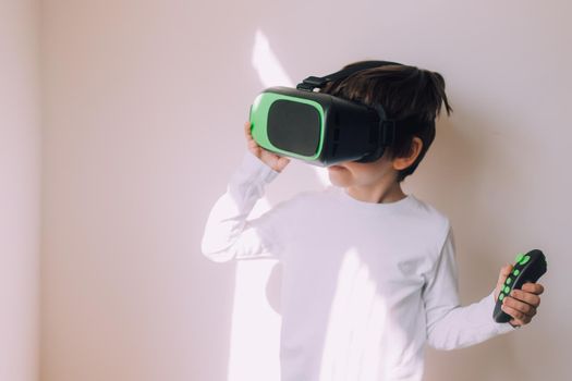 A boy is playing vr glasses on a white copyspace wall . An article about modern gadgets. An article about modern technologies. Place under the text