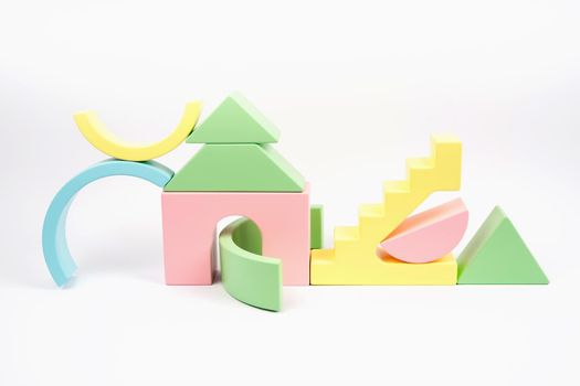 Abstract composition of wooden figures. Figures of yellow pink, blue and green. The wooden children's cubes is isolated on a white background. Zero waste toy.