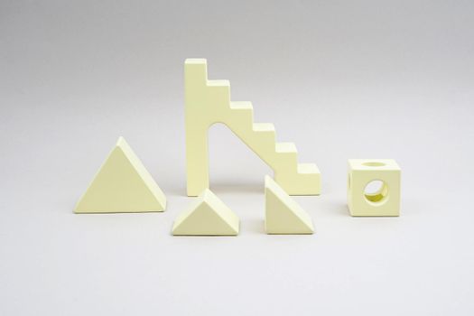 Children's wooden construction kit. Figures from a yellow wooden cubes. A toy for developing a child's creative thinking. Yellow details of a wooden constructor. Toys made of natural material.