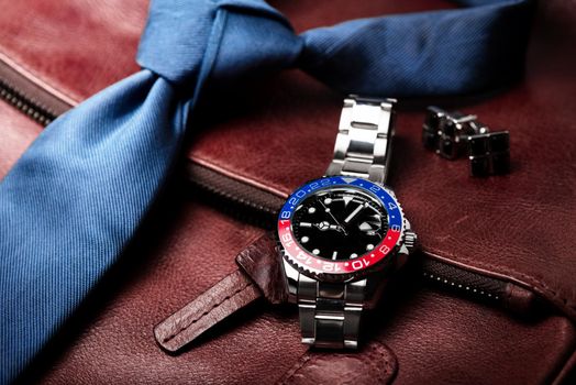 closeup luxury wristwatch for men with black dial blue-red bezel and stainless steel bracelet.