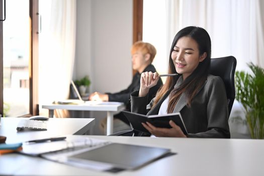 Beautiful businesswoman sitting on comfortable office chair and reading book.