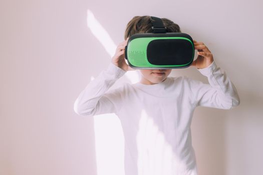 A boy is playing vr glasses on a white copyspace wall . An article about modern gadgets. An article about modern technologies. Place under the text